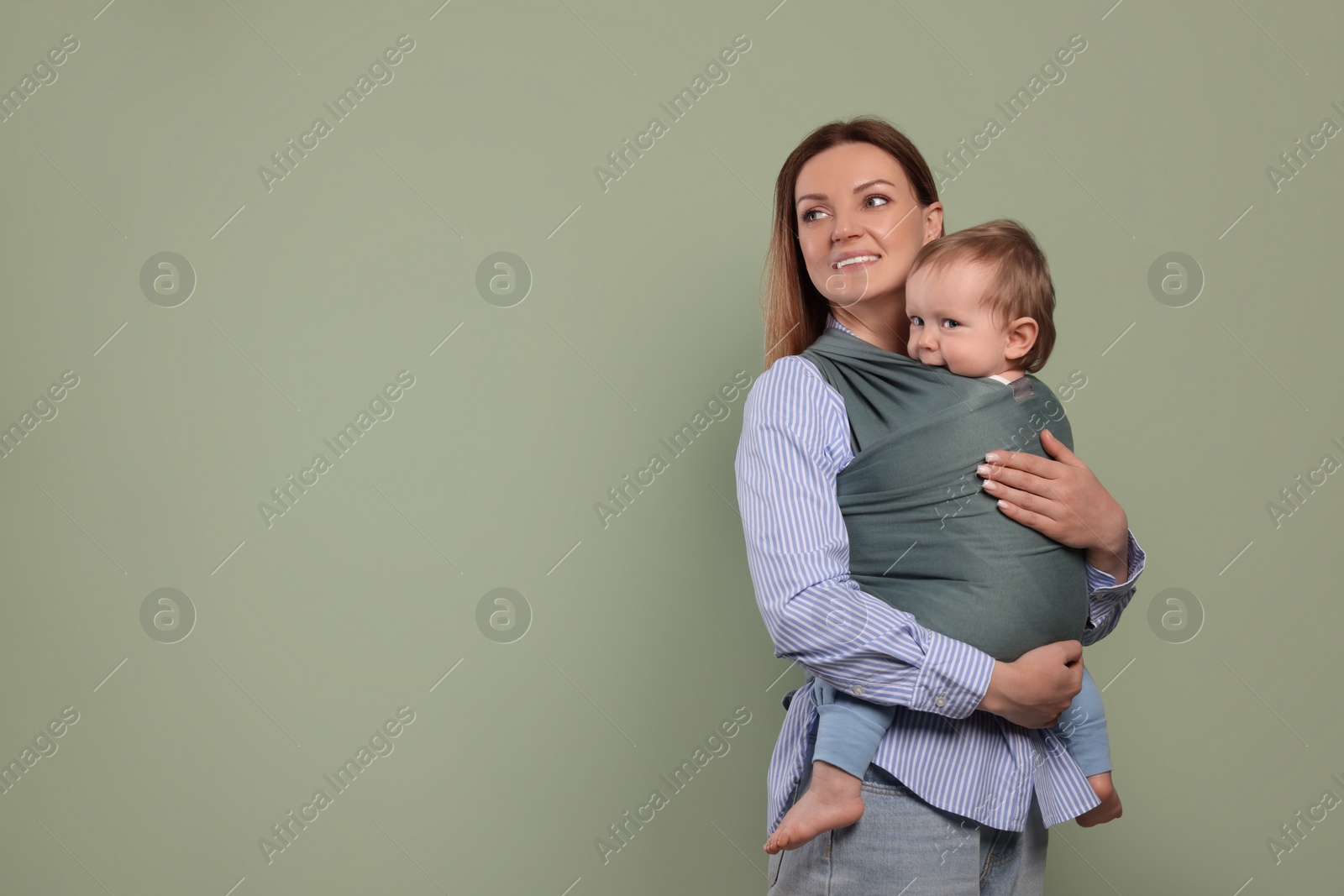 Photo of Mother holding her child in baby wrap on olive background. Space for text