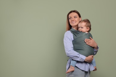 Photo of Mother holding her child in baby wrap on olive background. Space for text