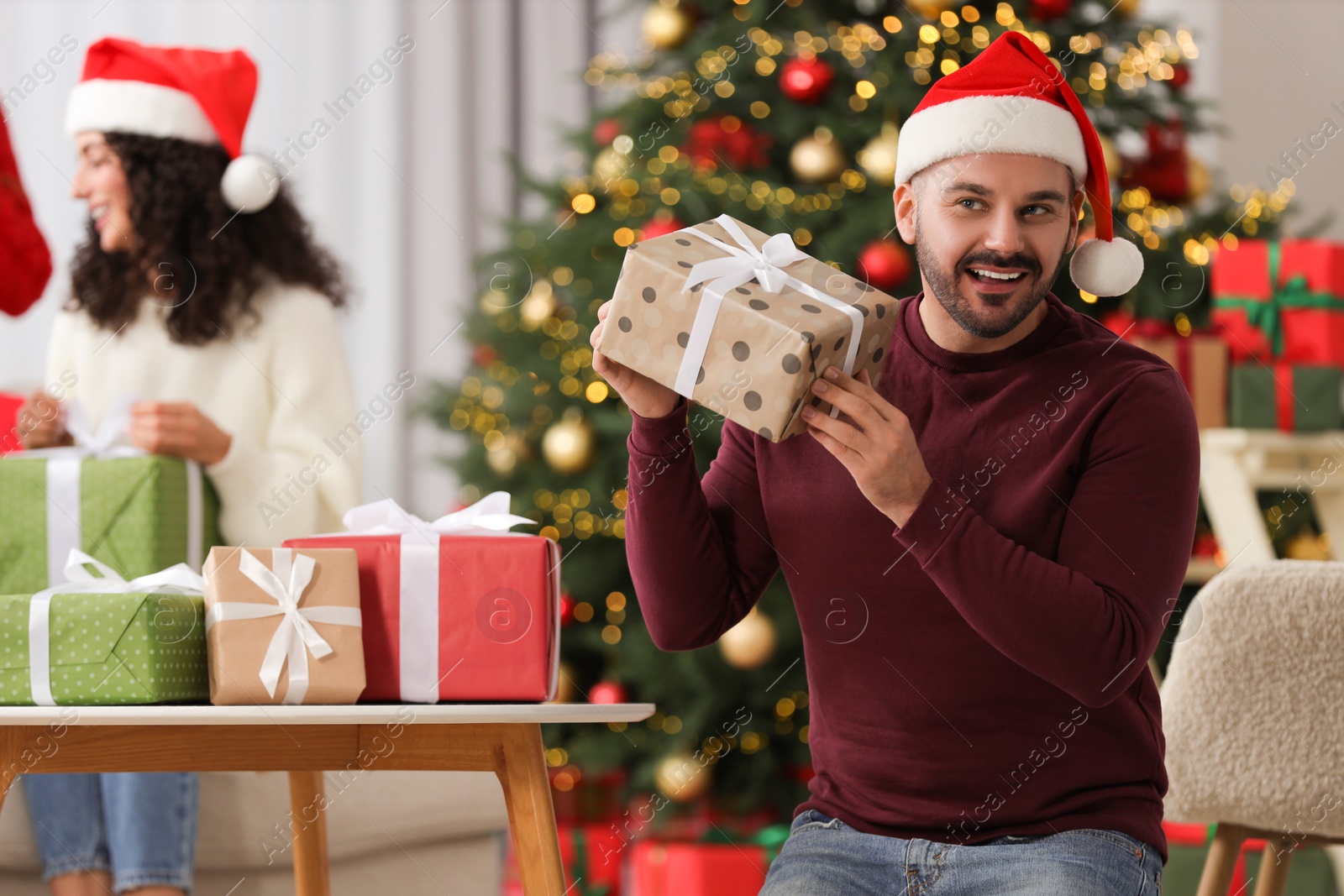 Photo of Christmas celebration in circle of friends. Happy man with gift box at home, selective focus