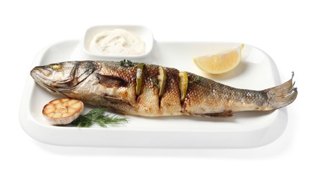 Photo of Plate with delicious baked sea bass fish, garlic, slice of lemon and sauce on white background