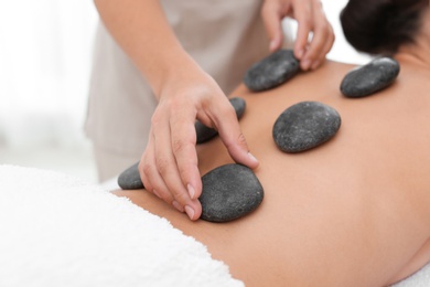 Beautiful young woman getting hot stone massage in spa salon