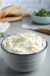 Photo of Bowl of tasty cream cheese on grey table