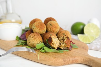 Photo of Delicious falafel balls with herbs on white wooden table, closeup