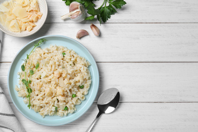 Delicious risotto with cheese on white wooden table, flat lay. Space for text