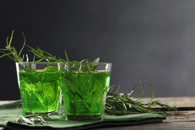 Photo of Glasses of refreshing tarragon drink on wooden table. Space for text