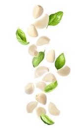 Image of Fresh peeled garlic cloves and basil leaves flying on white background