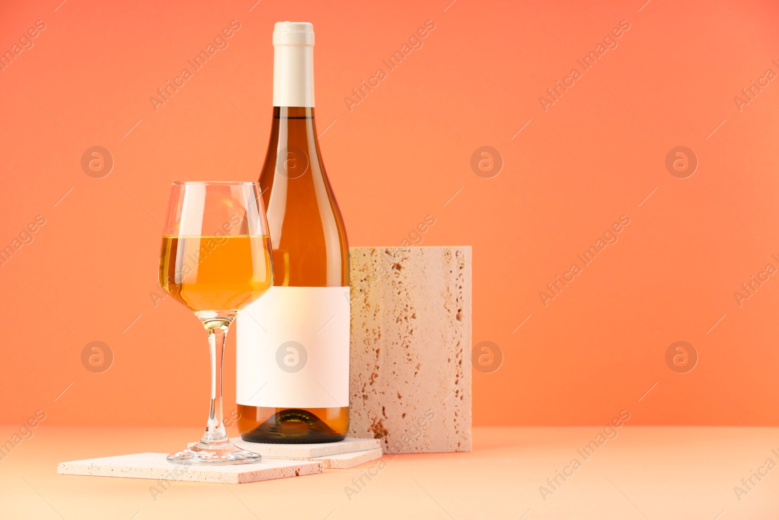 Photo of Stylish presentation of delicious wine in bottle and glass on orange background. Space for text