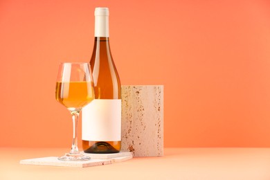 Stylish presentation of delicious wine in bottle and glass on orange background. Space for text