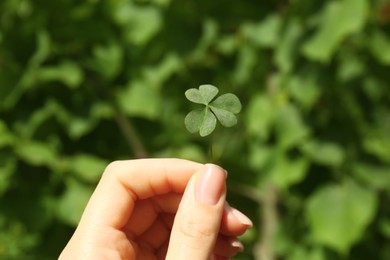 Photo of Woman holding green clover leaf outdoors, closeup