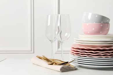 Photo of Beautiful ceramic dishware, glasses and cutlery on white marble table. Space for text