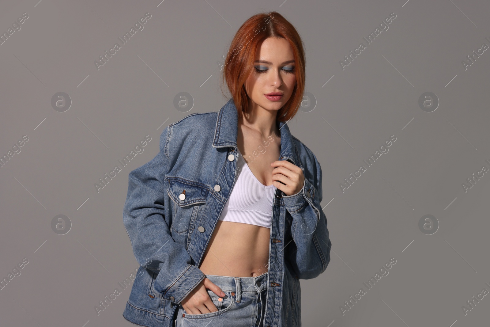 Photo of Beautiful young woman in denim jacket on gray background