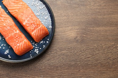 Fresh raw salmon with salt on wooden table, top view. Space for text