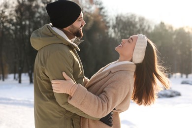 Beautiful happy couple in snowy park on winter day