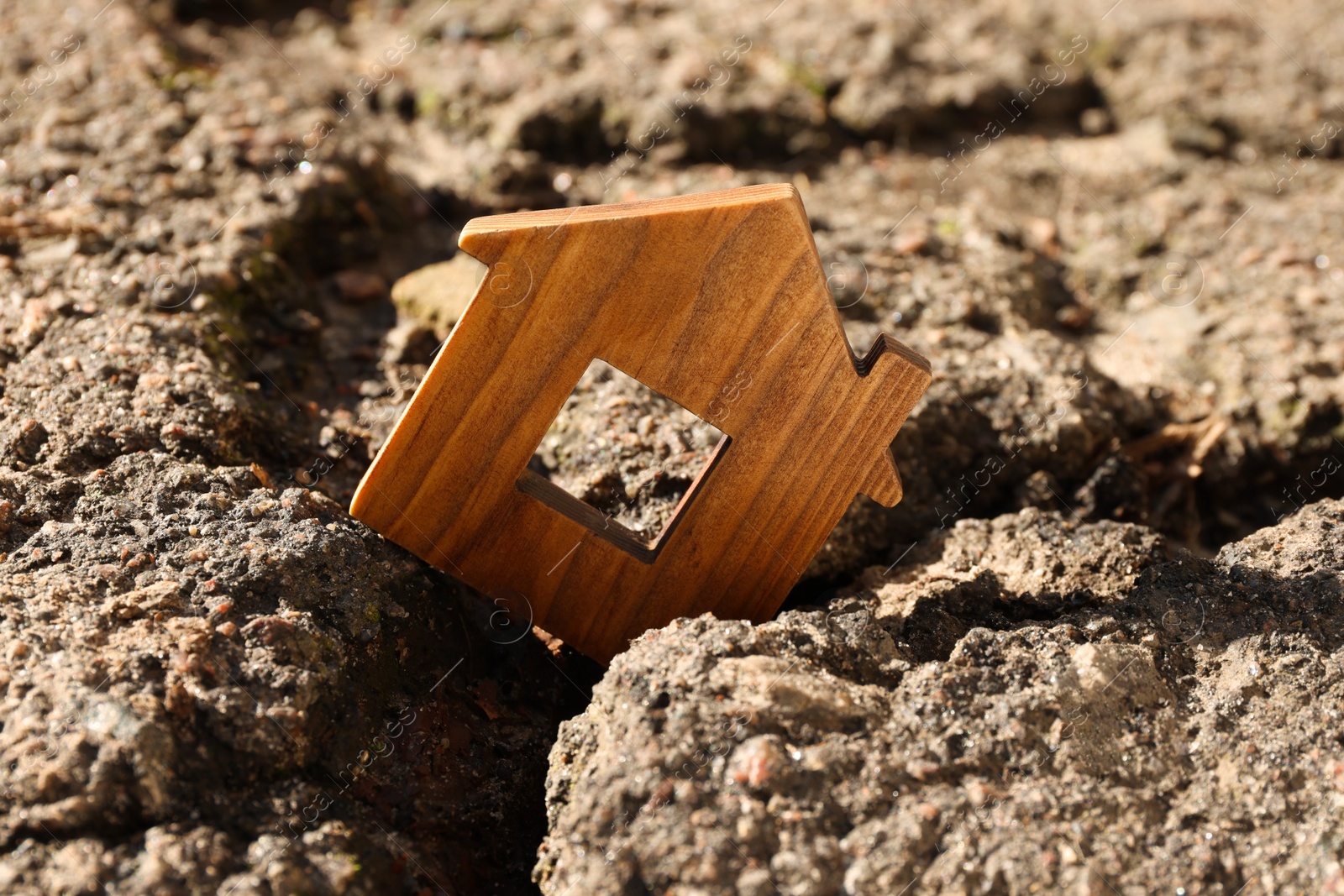 Photo of Wooden house model in cracked asphalt. Earthquake disaster