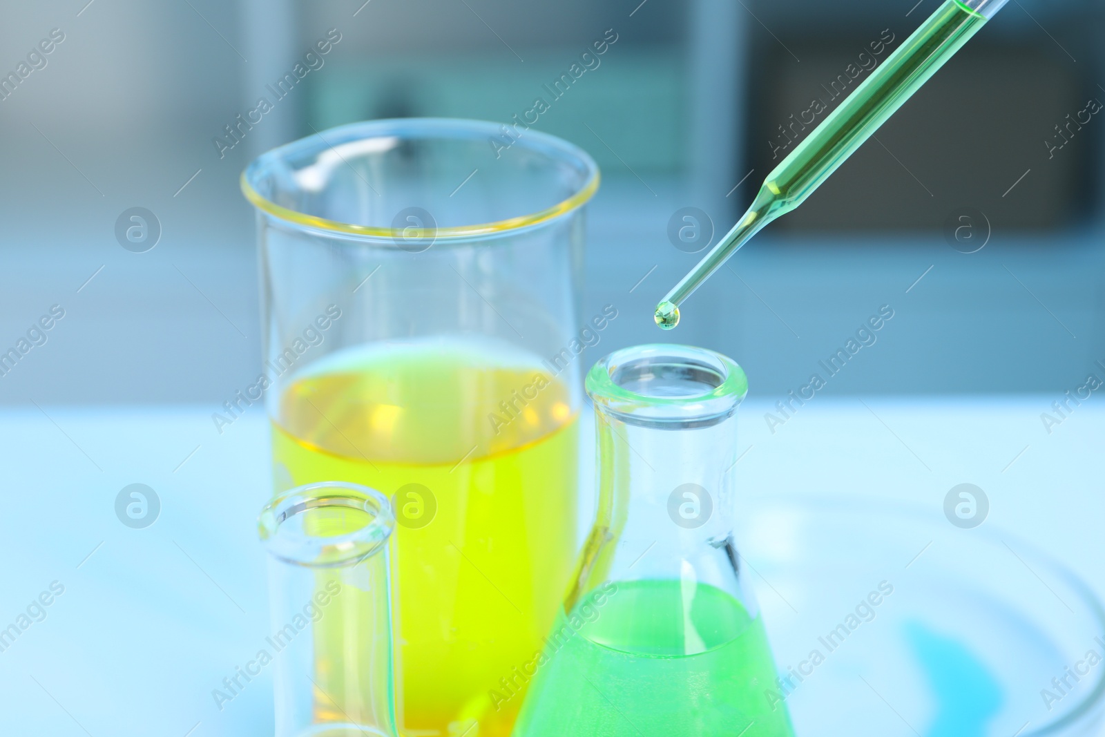 Photo of Laboratory analysis. Dripping liquid into flask at white table indoors, closeup