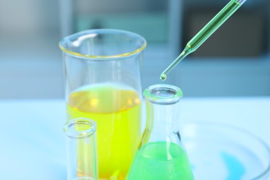 Laboratory analysis. Dripping liquid into flask at white table indoors, closeup