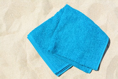 Photo of Soft blue beach towel on sand, top view