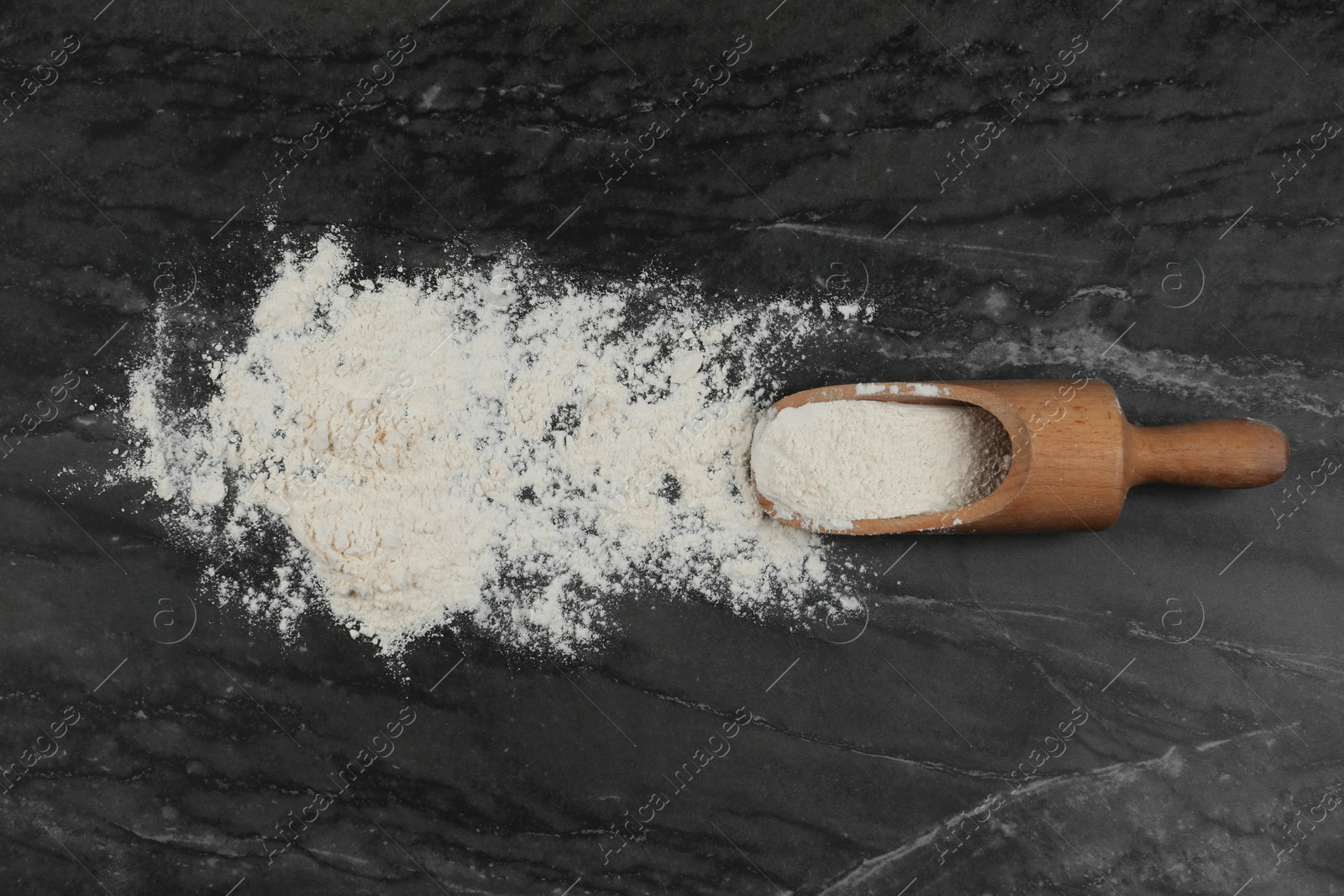Photo of Flour and wooden scoop on grey marble table, flat lay