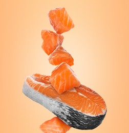 Cut fresh salmon falling on pale orange background