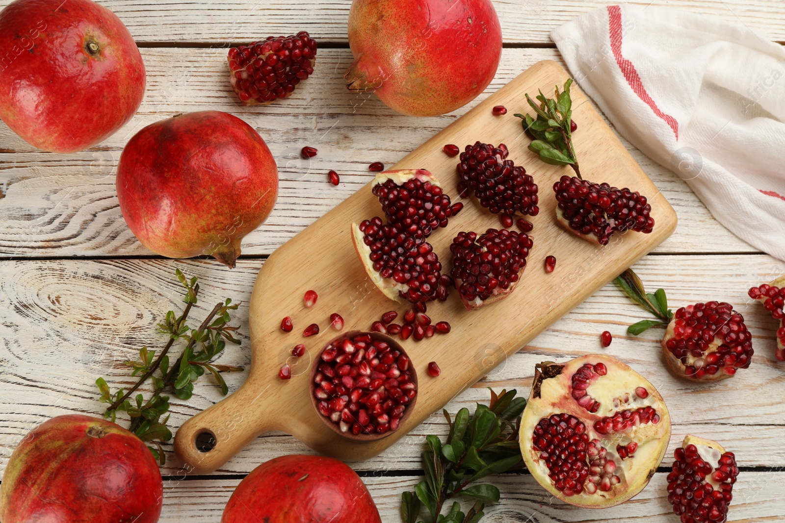 Photo of Delicious ripe pomegranates on white wooden table, flat lay