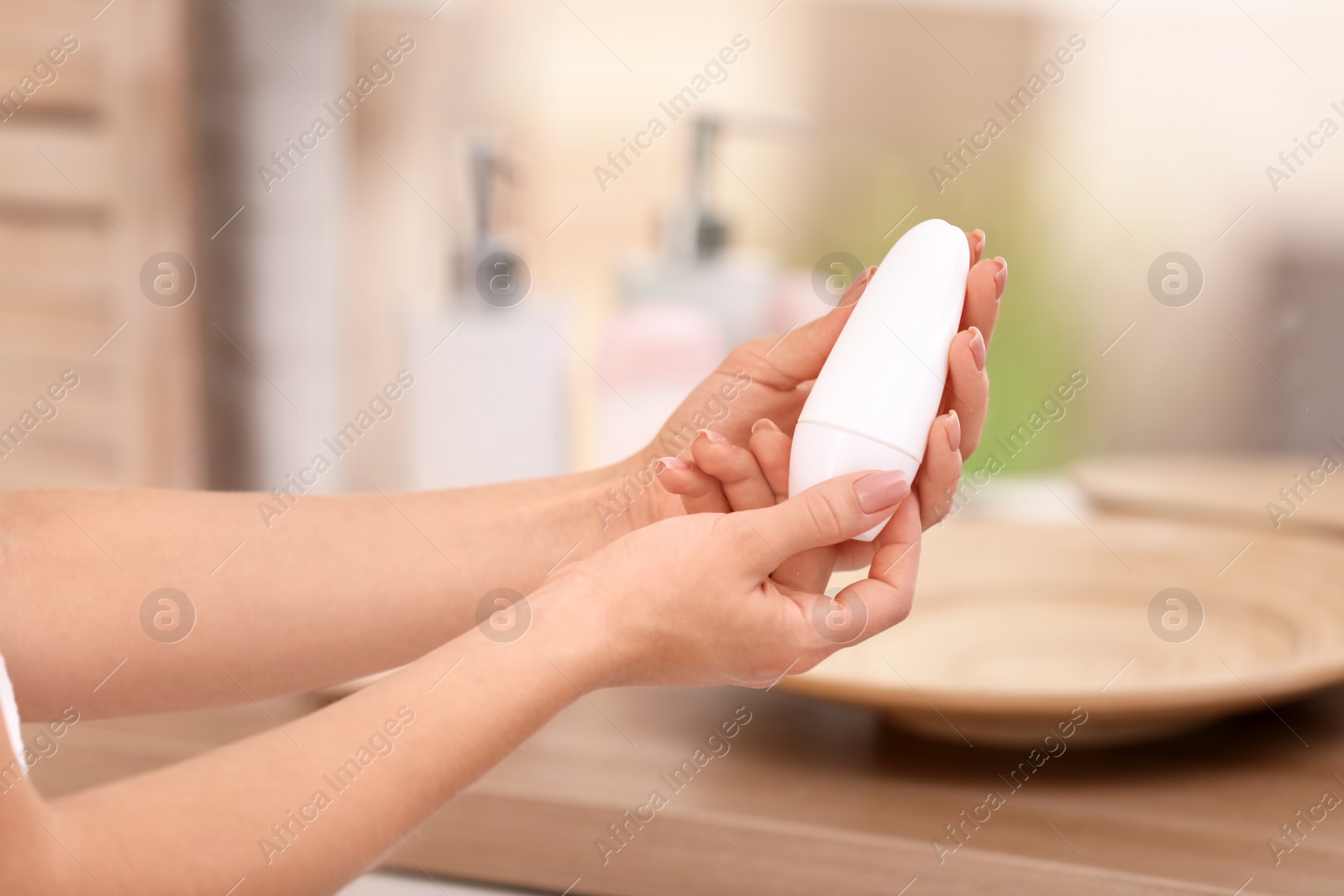 Photo of Young woman holding deodorant in bathroom, closeup