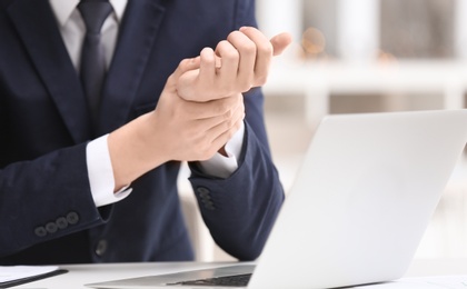 Young man suffering from wrist pain in office