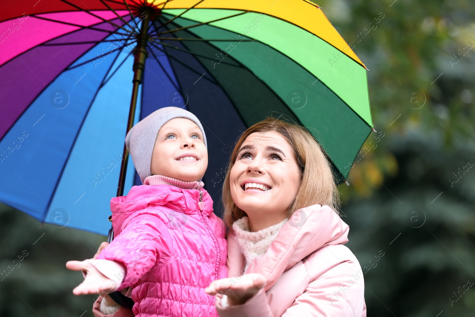 Photo of Mother and daughter with umbrella in autumn park on rainy day