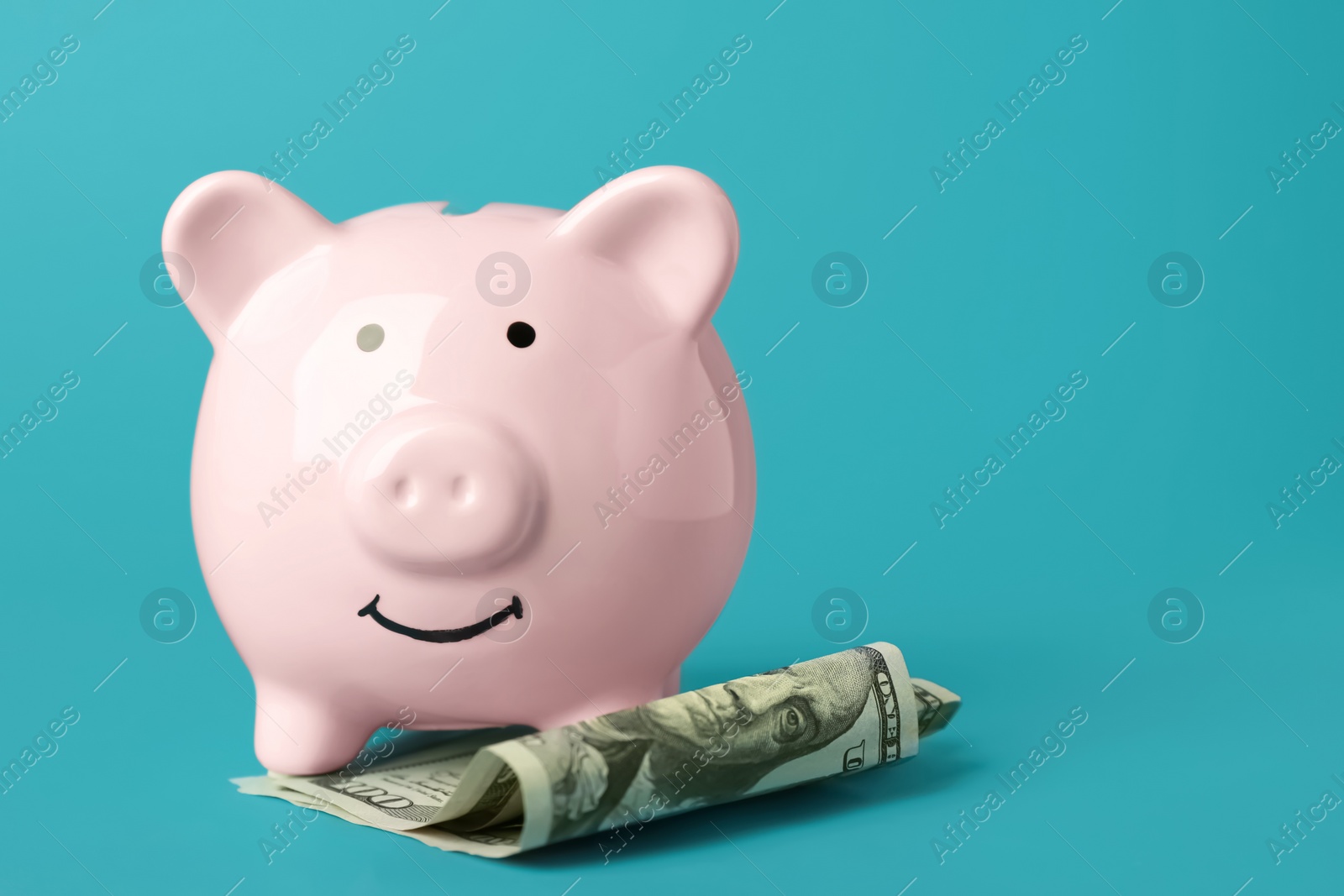 Photo of Ceramic piggy bank and banknotes on turquoise background. Space for text