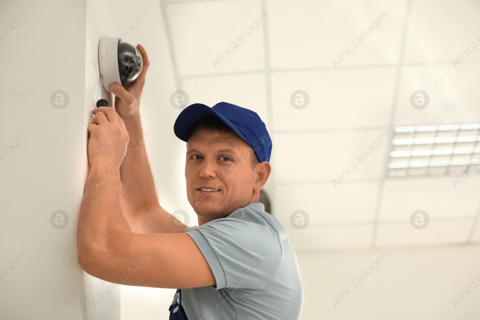 Photo of Technician installing CCTV camera on wall indoors