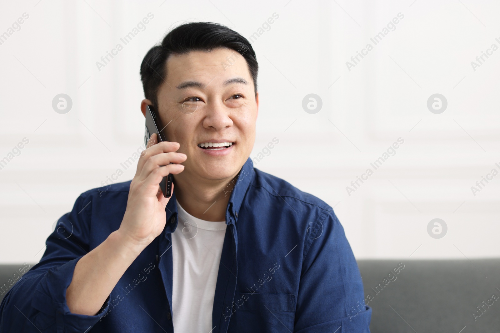 Photo of Portrait of smiling businessman talking by smartphone indoors. Space for text