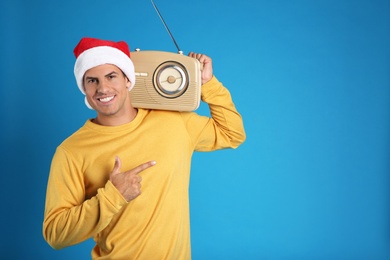 Photo of Happy man with vintage radio on blue background, space for text. Christmas music