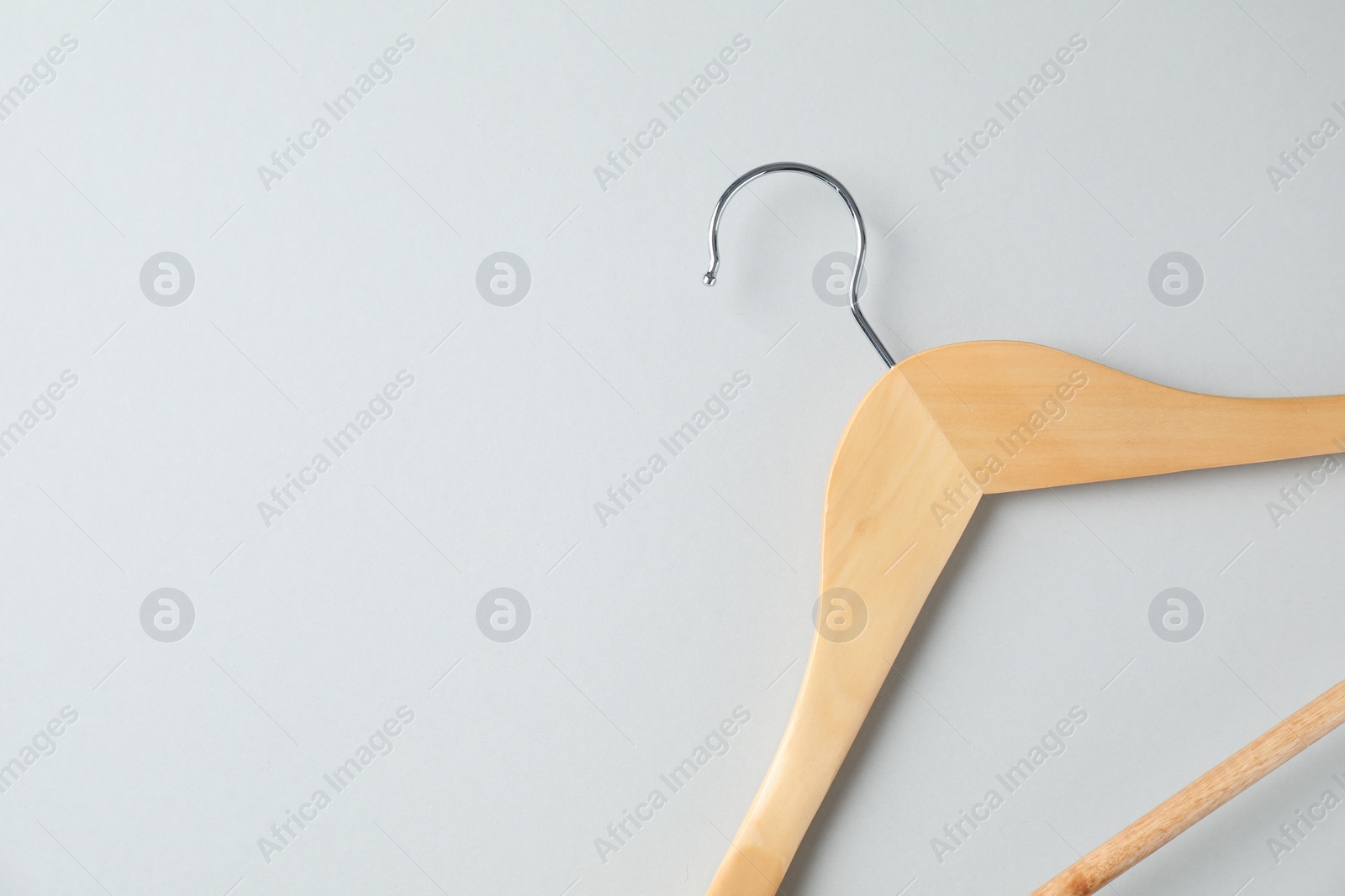 Photo of Empty wooden hanger on light grey background, top view. Space for text