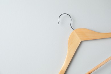 Empty wooden hanger on light grey background, top view. Space for text