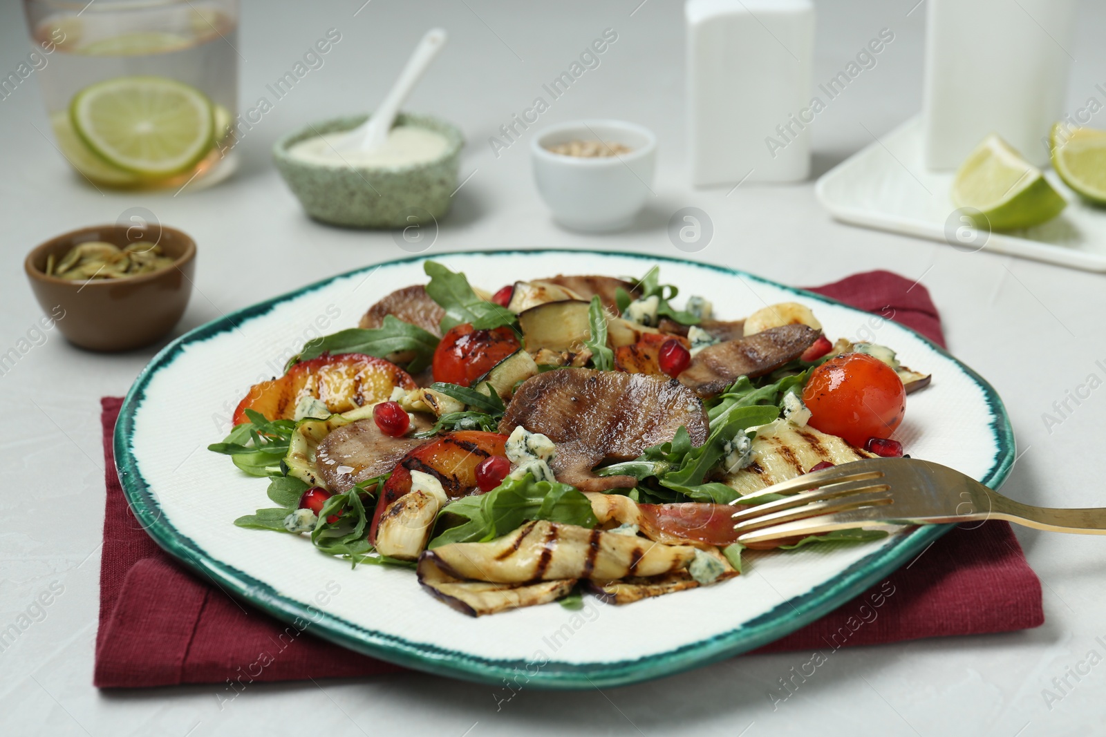 Photo of Delicious salad with beef tongue, grilled vegetables, peach, blue cheese and fork served on white table