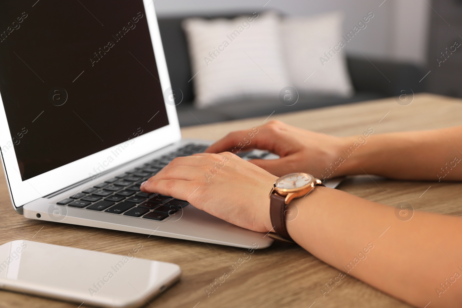 Photo of Woman working with laptop at wooden table indoors, closeup