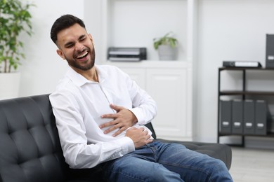 Photo of Handsome young man laughing on sofa in office