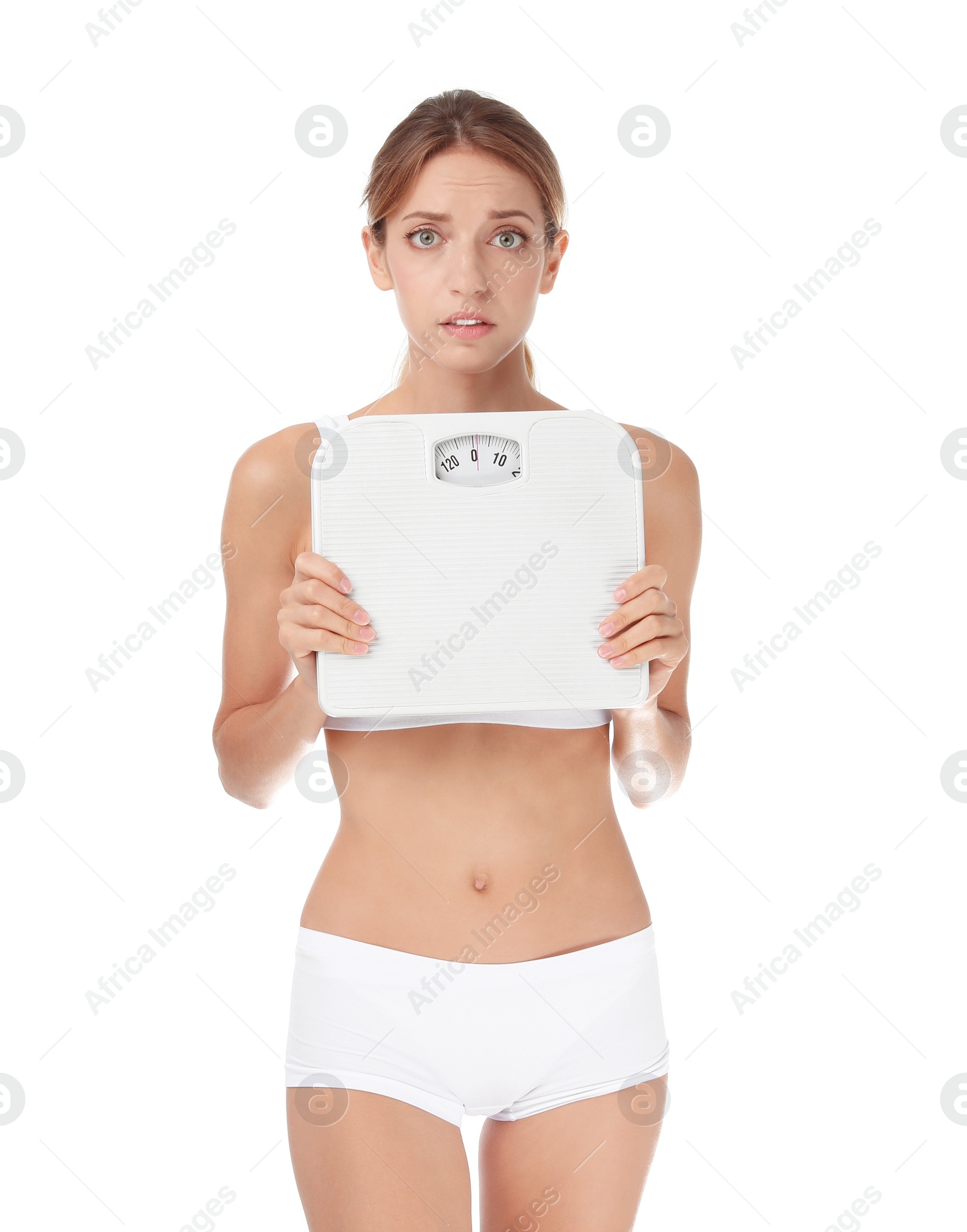 Photo of Worried young woman holding bathroom scales on white background. Weight loss diet