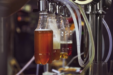 Photo of New modern beer taps with plastic bottles on bar counter in pub