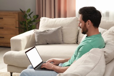 Man using laptop on sofa at home