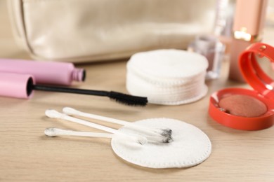 Dirty cotton pads, swabs and cosmetic products on wooden table