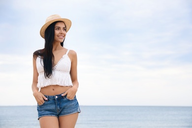 Photo of Beautiful young woman with beach hat near sea. Space for text