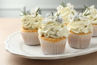 Photo of Tasty Easter cupcakes with vanilla cream on wooden table, closeup