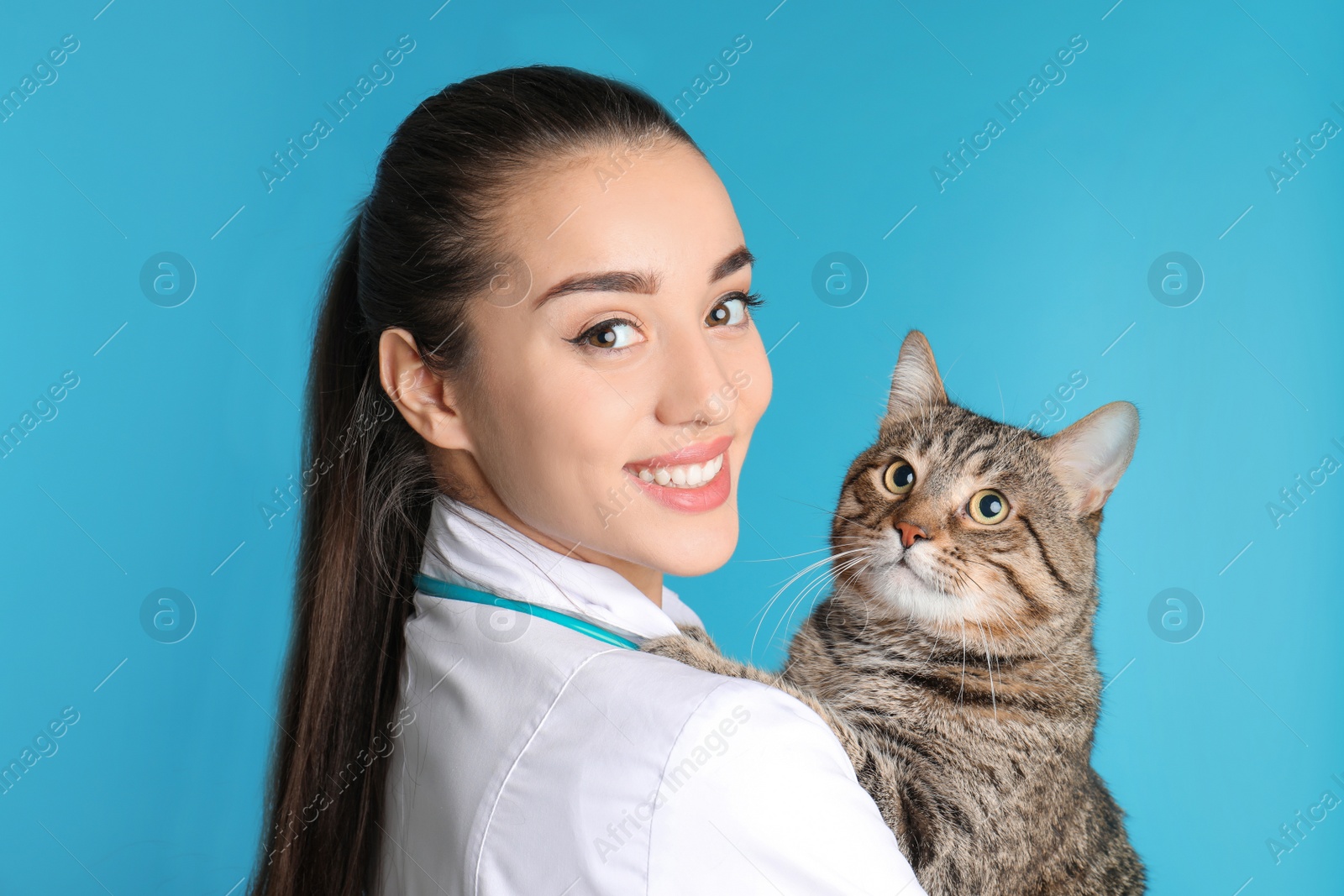 Photo of Veterinarian doc with cat on color background