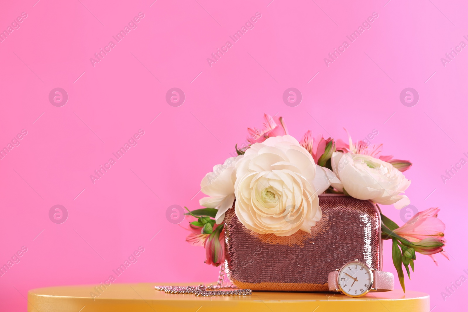 Photo of Elegant handbag with spring flowers on table against pink background, space for text