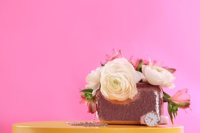 Photo of Elegant handbag with spring flowers on table against pink background, space for text