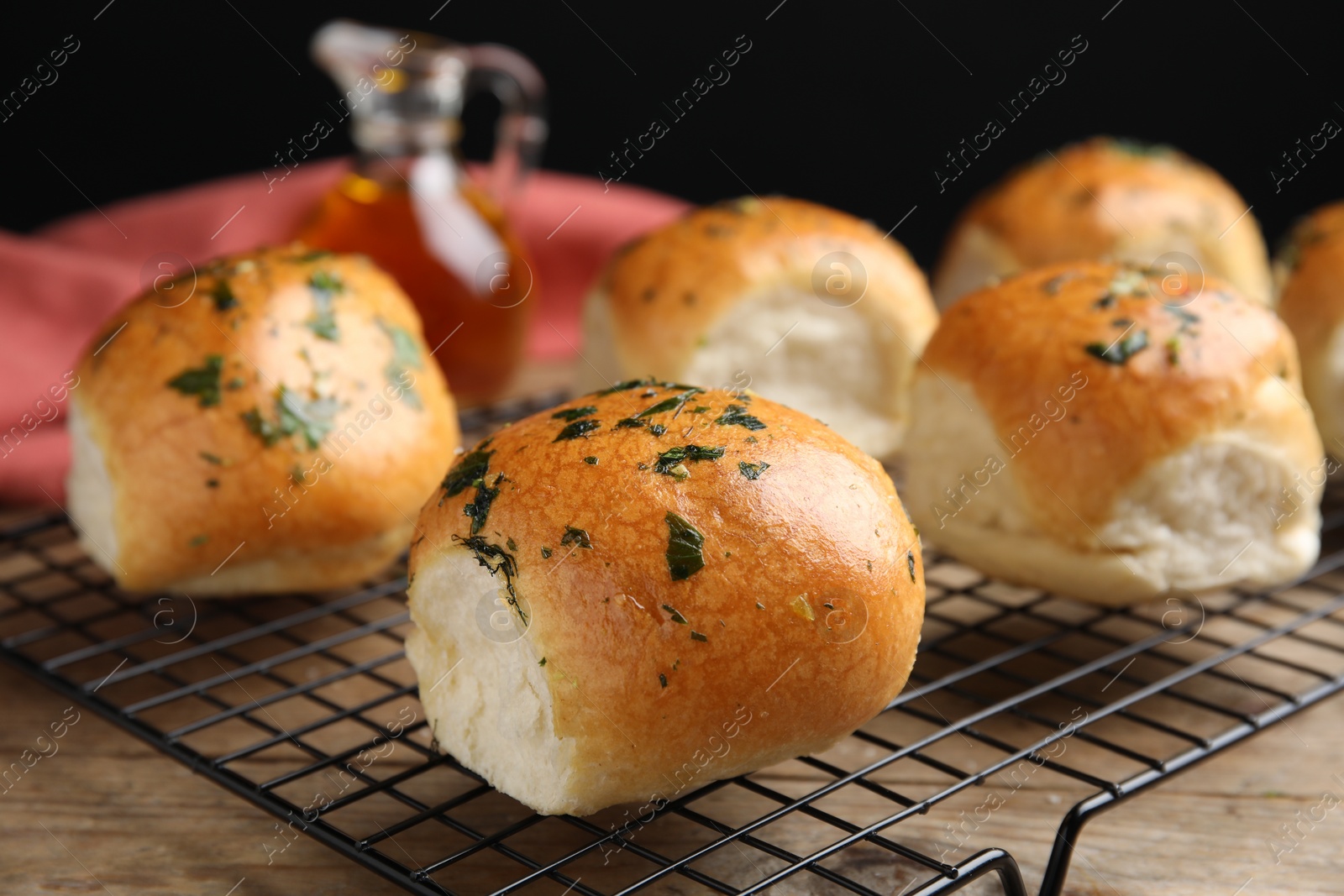 Photo of Traditional Ukrainian bread (Pampushky) with garlic on baking grid, closeup