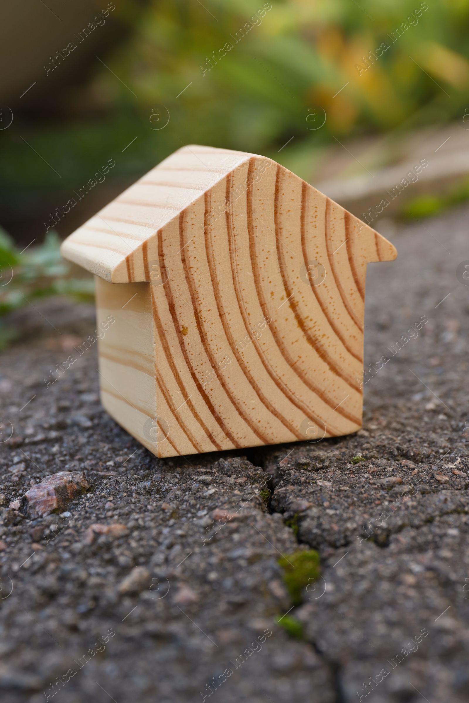 Photo of Wooden house model on cracked asphalt. Earthquake disaster