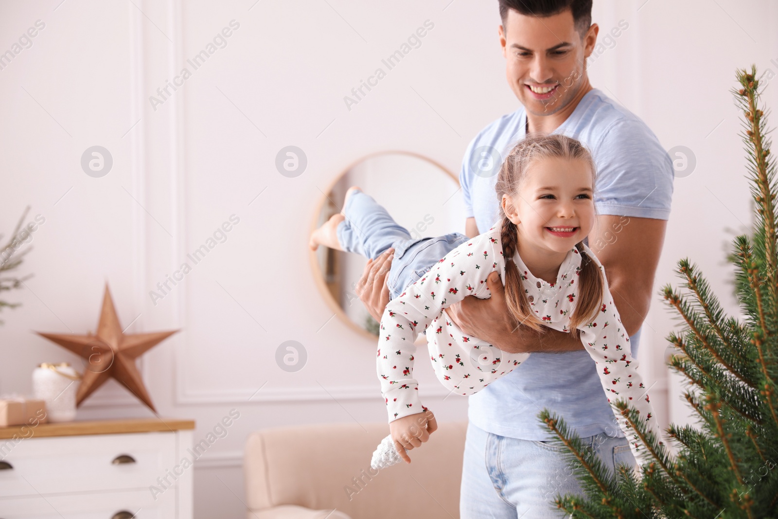 Photo of Father with his cute daughter having fun near fir tree at home. Christmas atmosphere