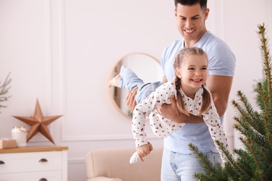 Photo of Father with his cute daughter having fun near fir tree at home. Christmas atmosphere