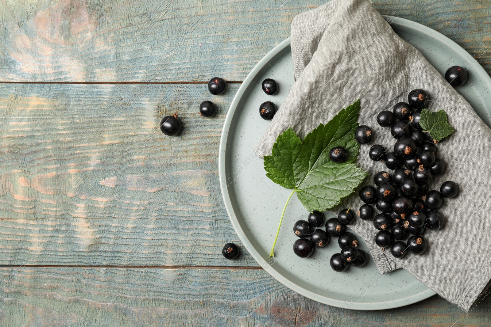 Photo of Ripe blackcurrants and leaves on wooden rustic table, flat lay. Space for text